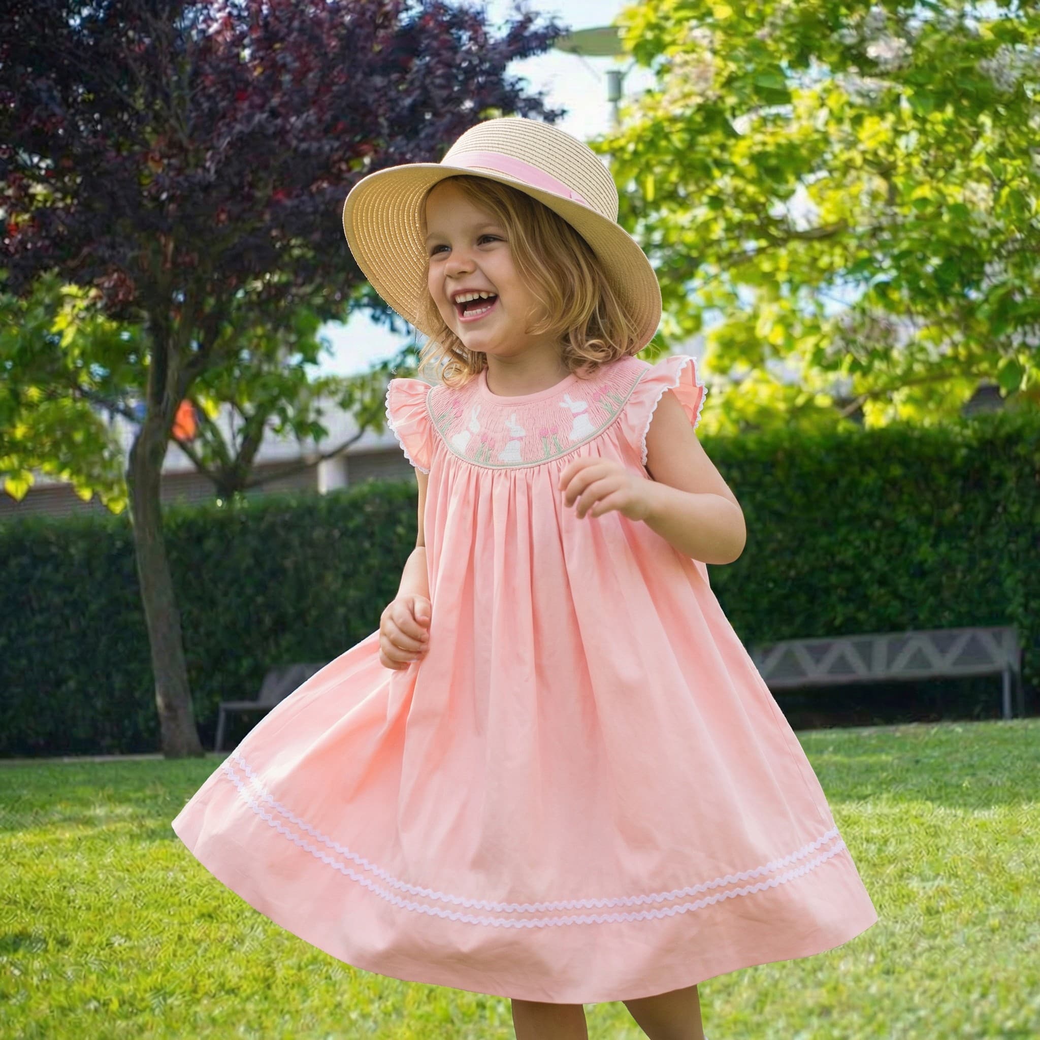 Little girl in pink embroidered dress twirling in garden