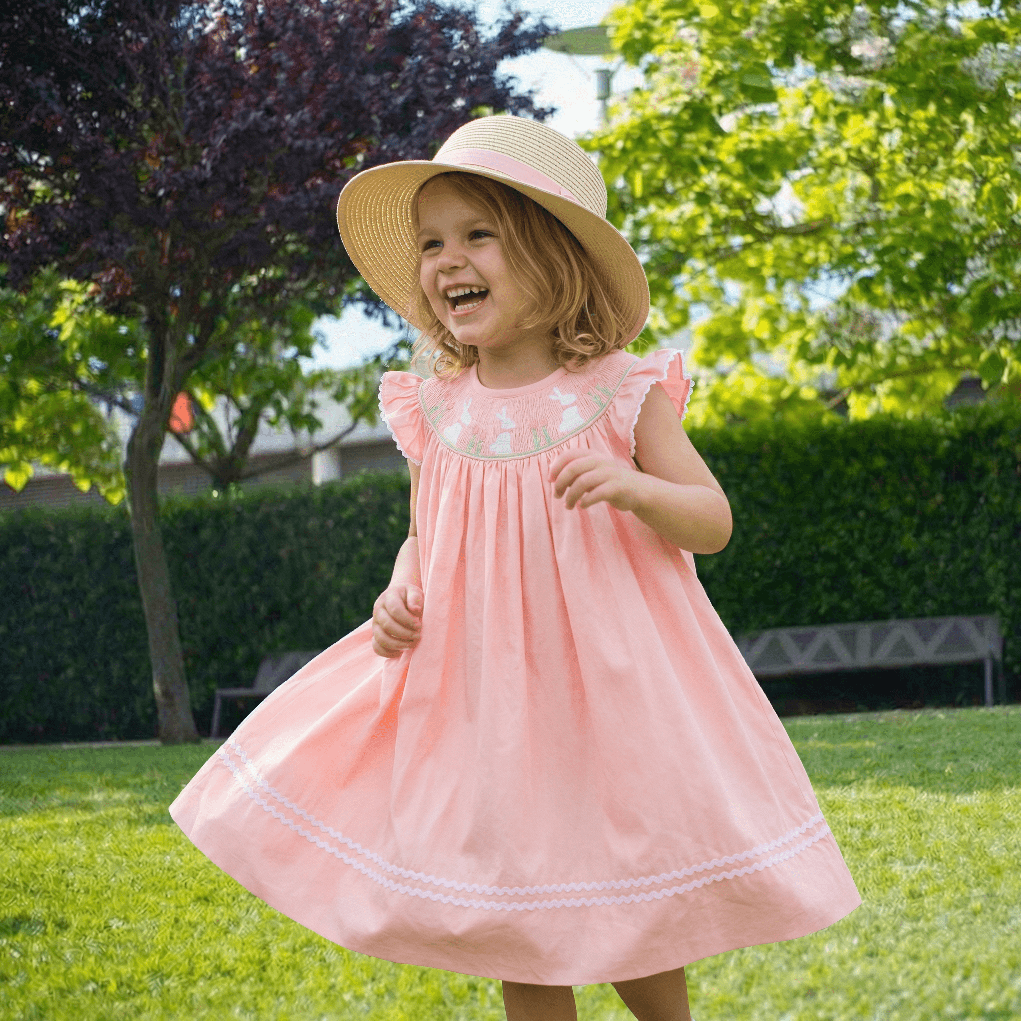 Little girl in pink embroidered dress twirling in garden